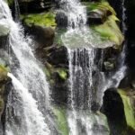 A picturesque waterfall cascading over moss-covered rocks in a tranquil natural setting.